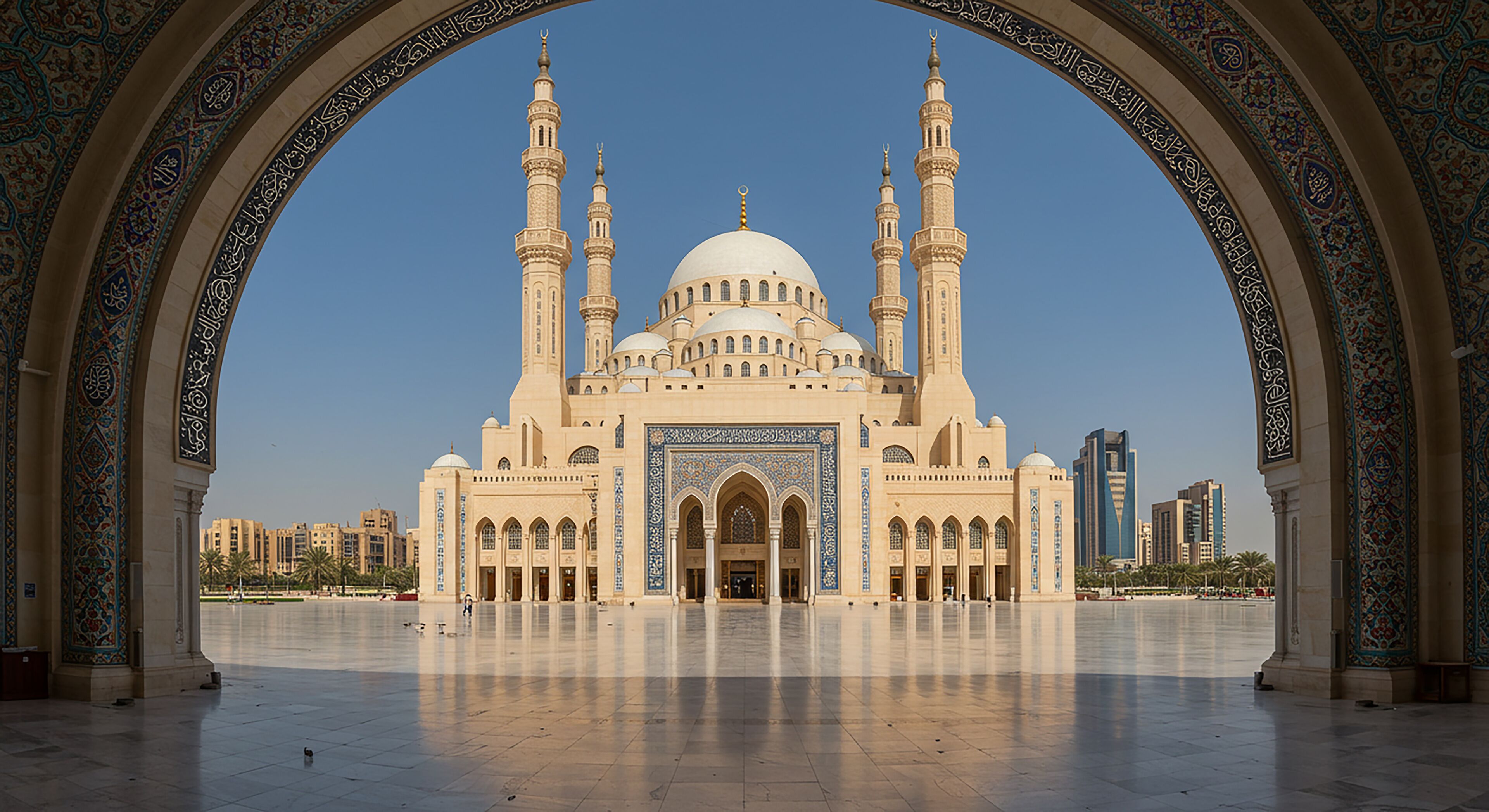 Stunning view of Sharjah Mosque, UAE. Grand domes and tall minarets framed by ornate archway under soft blue sky.

