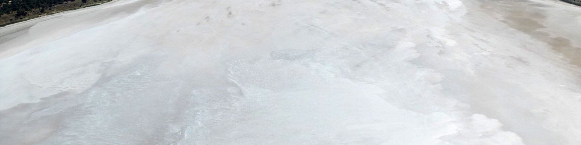 A vast white sandy area with a clear blue ocean in the background.