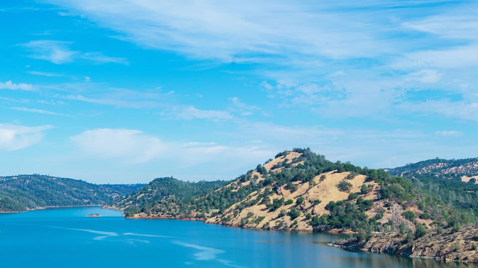 A clear blue lake surrounded by forested hills.