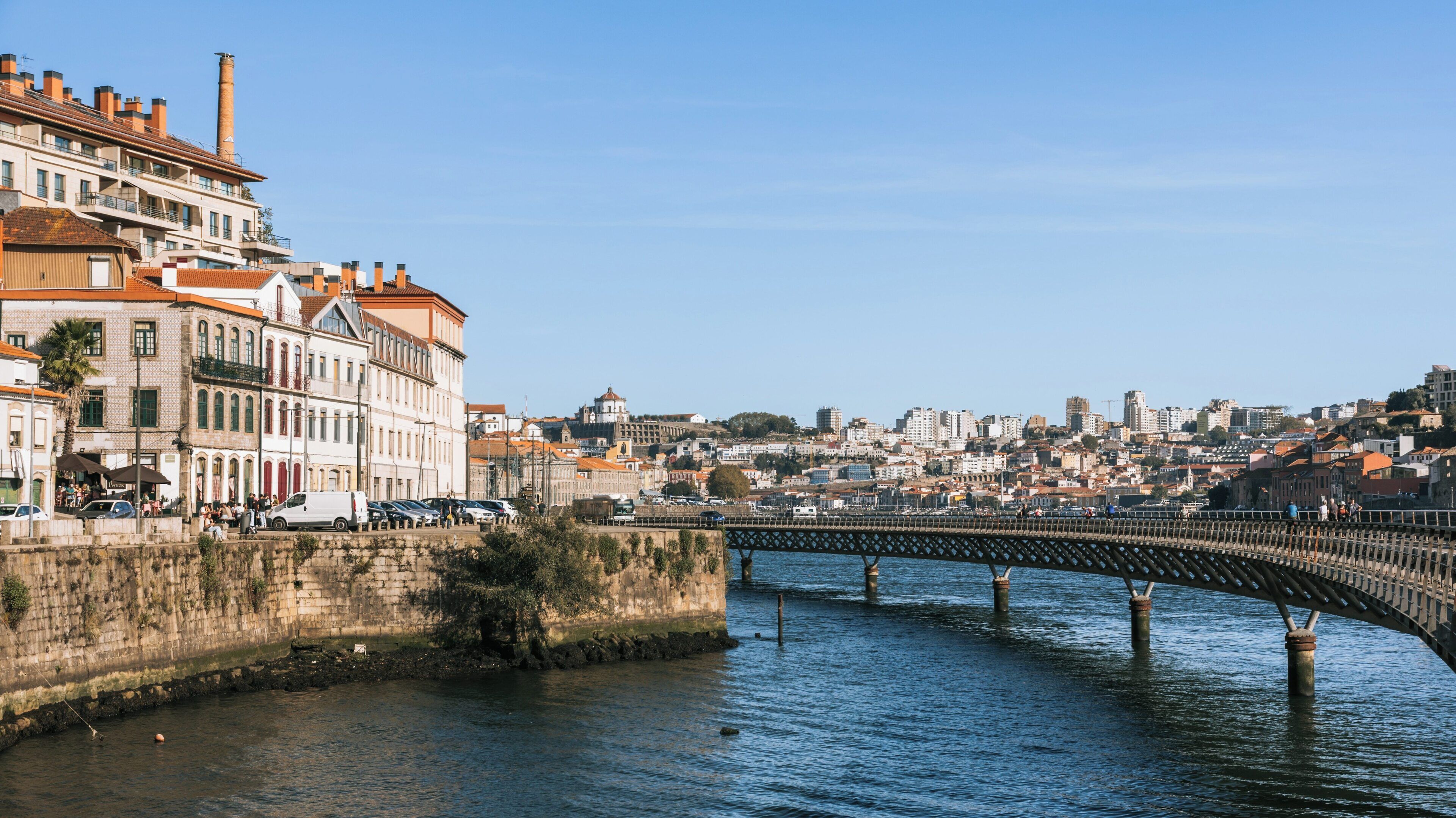 Un río con un puente, edificios históricos y un paisaje urbano al fondo.