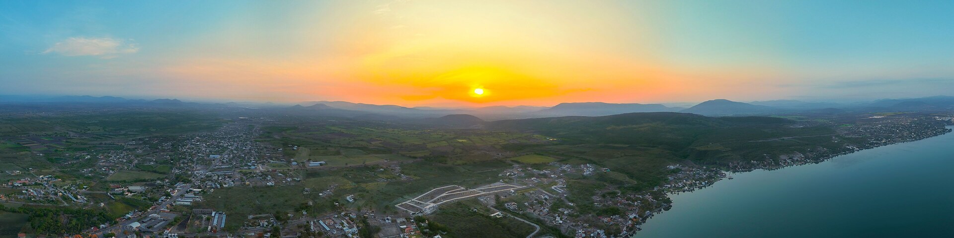 Aerial View of Tequesquitengo at Dawn: Lake, Picturesque Town, and Rising Sun Behind Distant Mountains Creating a Stunning Landscape