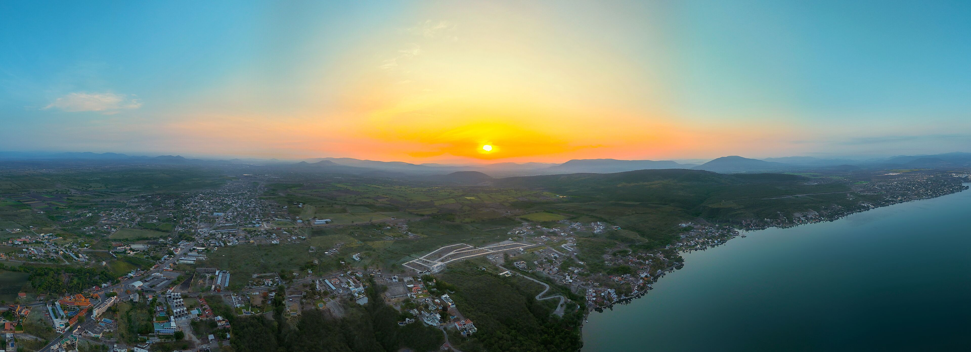 A coastal town with a river, surrounded by hills and mountains.