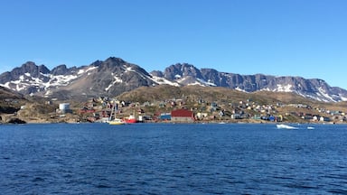 A coastal village with colorful houses and a mountain range in the background.