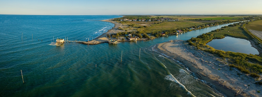 beautiful panorama of the valleys near Ravenna (Fiumi Uniti) where the river flows into the sea with the typical fishermen's huts at sunset