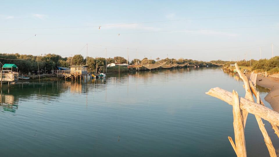 A calm river with wooden walkways and small buildings along the banks.