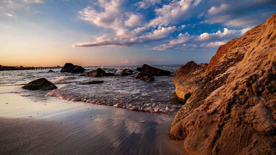 A rocky beach with waves at sunset.