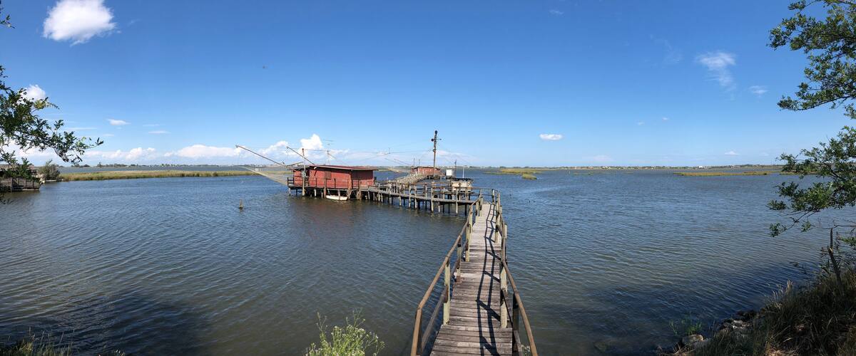 A wooden pier leading to a red building on a calm lake with clear skies.