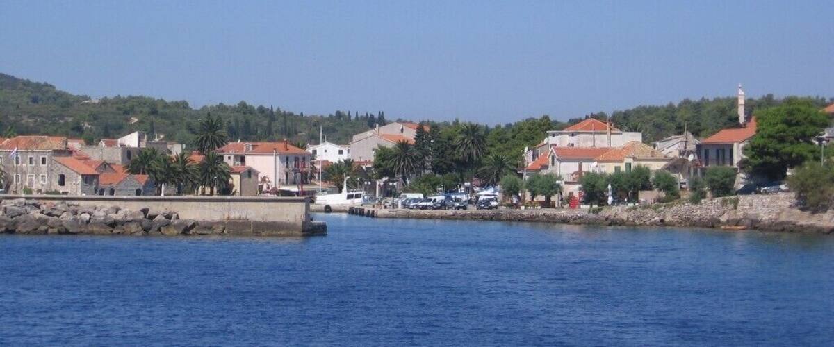 A coastal town with buildings, a pier, and a clear blue sky.