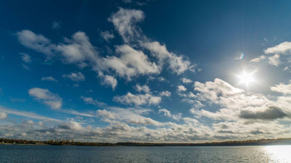 A lake with a clear sky and scattered clouds.