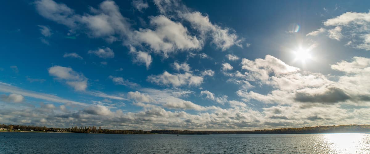 A lake with a clear sky and scattered clouds.