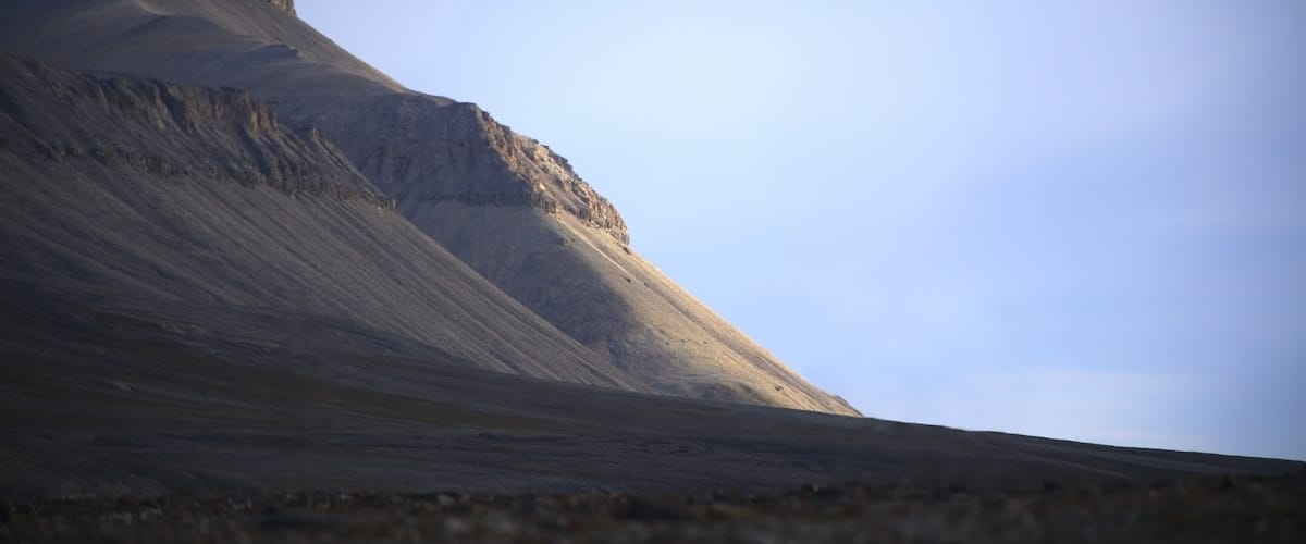 A large, steep mountain slope under a clear sky.