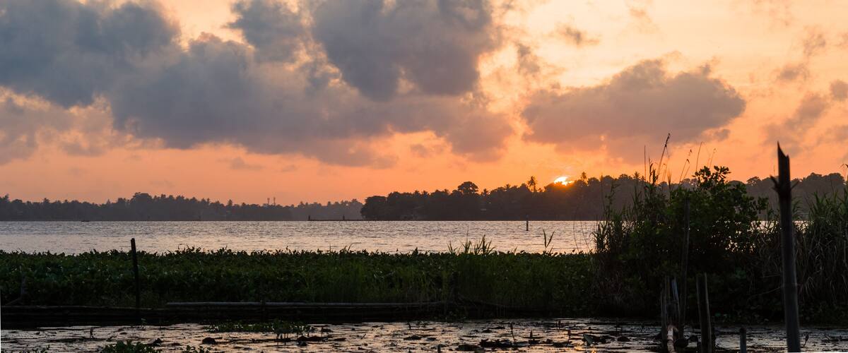 A sunset over a body of water with a distant shoreline and vegetation.