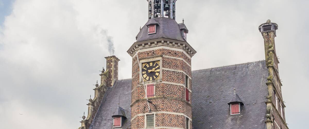 A historic building with a clock tower and red shutters.