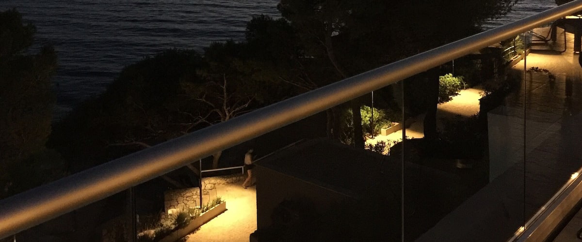 A balcony overlooking a body of water at dusk with a distant shoreline and trees.