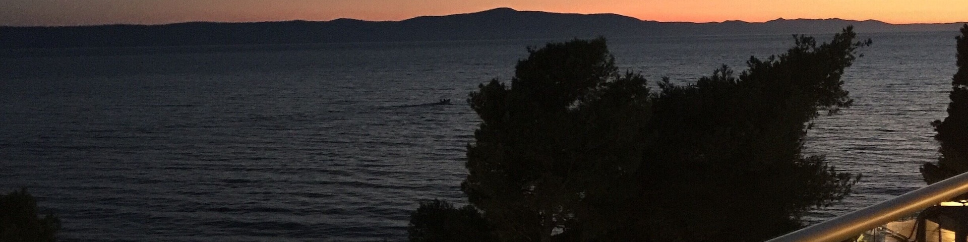 A balcony overlooking a body of water at dusk with a distant shoreline and trees.