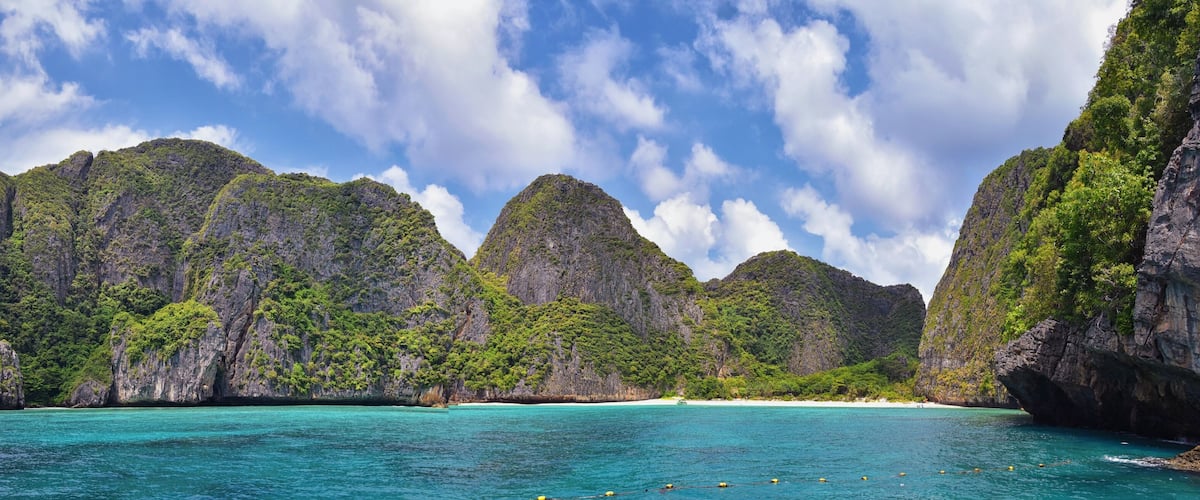 A coastal landscape with towering limestone cliffs and turquoise waters.