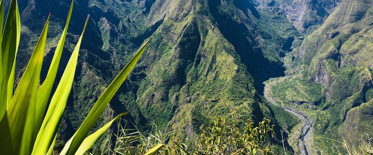 A mountain range with a prominent peak, lush green valleys, and a river winding through the landscape.