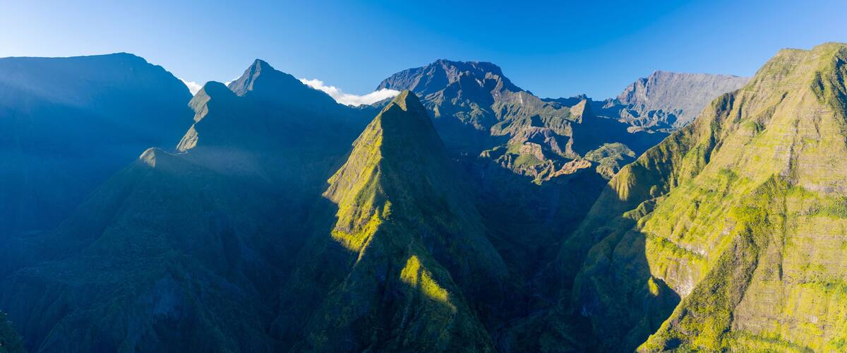 A mountain range with steep, green slopes and a prominent peak.