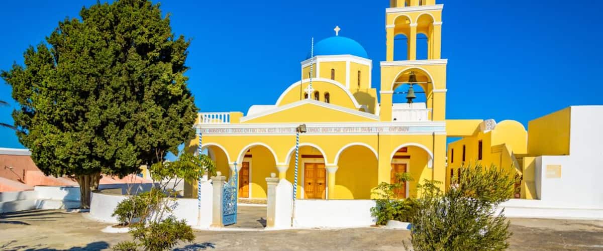 A yellow church with a blue dome and bell tower.