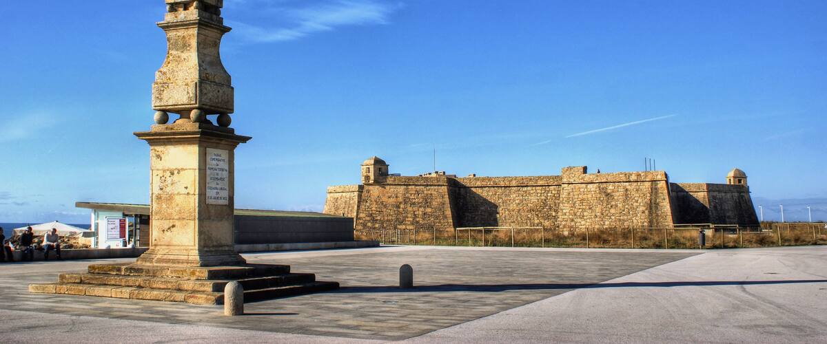 A historic fort with a tall, ornate monument in the foreground.