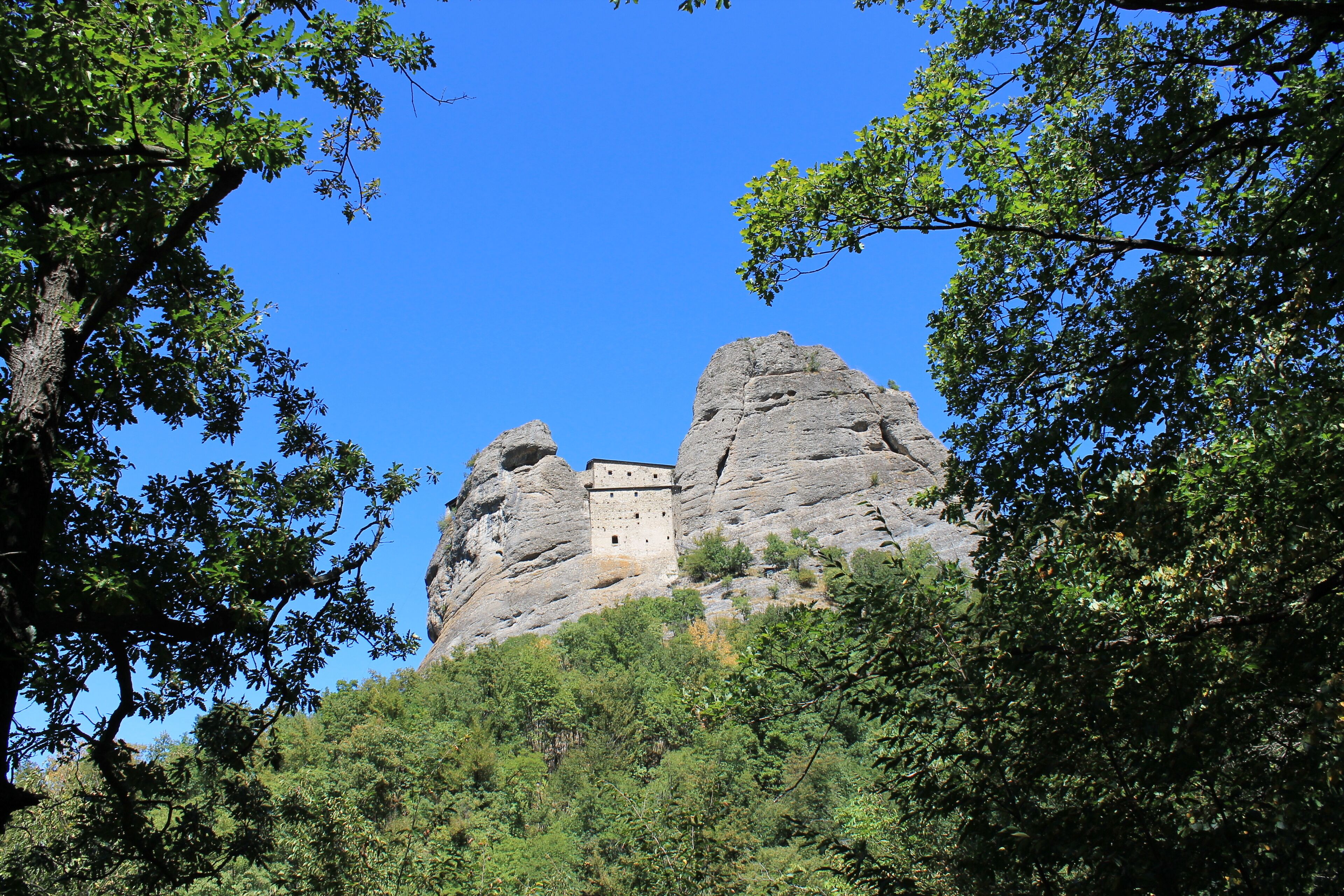 A castle perched atop a rocky hill, surrounded by lush greenery.