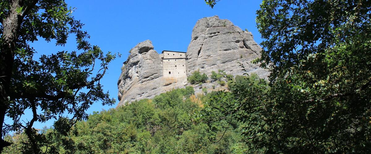 A castle perched atop a rocky hill, surrounded by lush greenery.