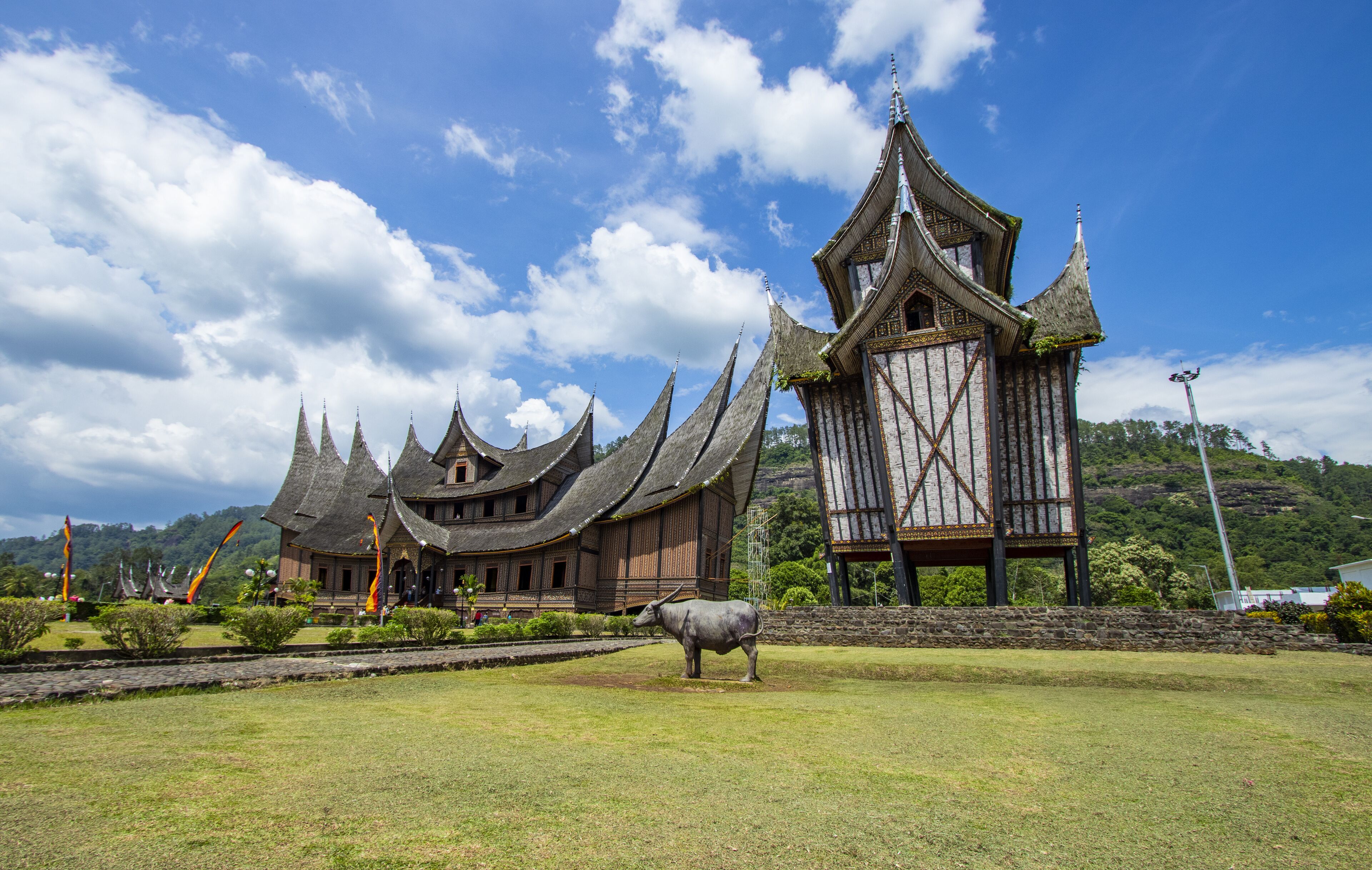 A traditional building with multiple pointed roofs and a large bull statue in front.