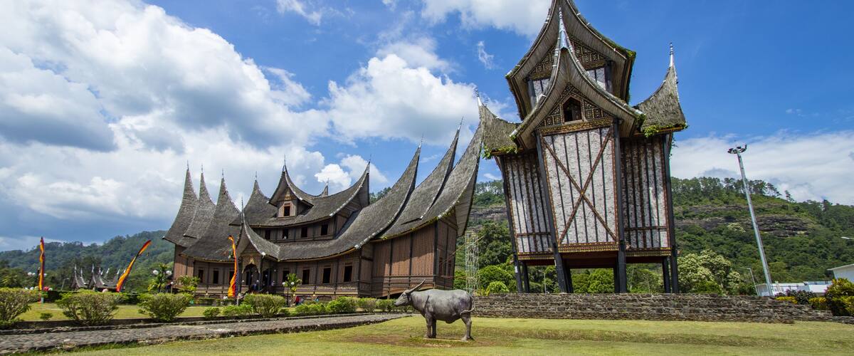 A traditional building with multiple pointed roofs and a large bull statue in front.