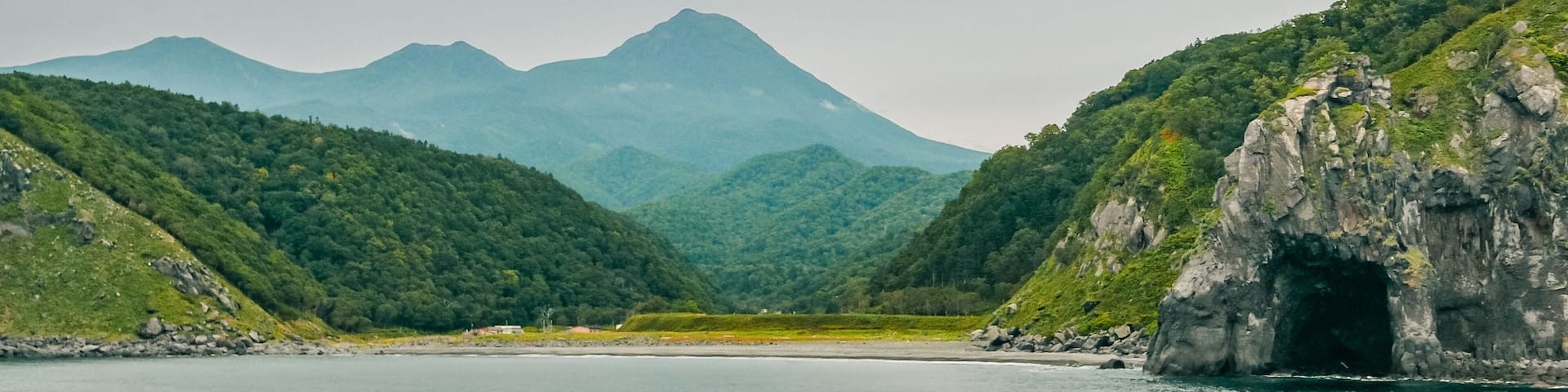 A distant view on a late summer afternoon from a sightseeing cruiser over the famous landmarks of Iwabetsu River terrace and Mt. Rausu in Shiretoko Peninsula, East Hokkaido, Japan.