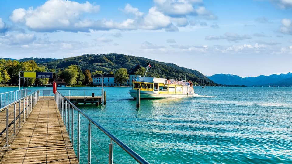 A wooden pier extending into a lake with a boat docked at the end.