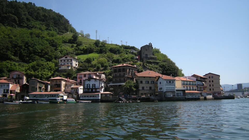 A lakeside town with buildings on a hillside and a historic tower.