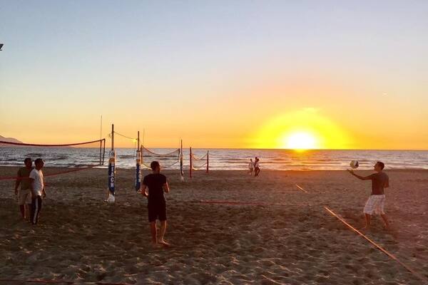Un match de volleyball de plage au coucher du soleil, avec des joueurs et un filet de volleyball.