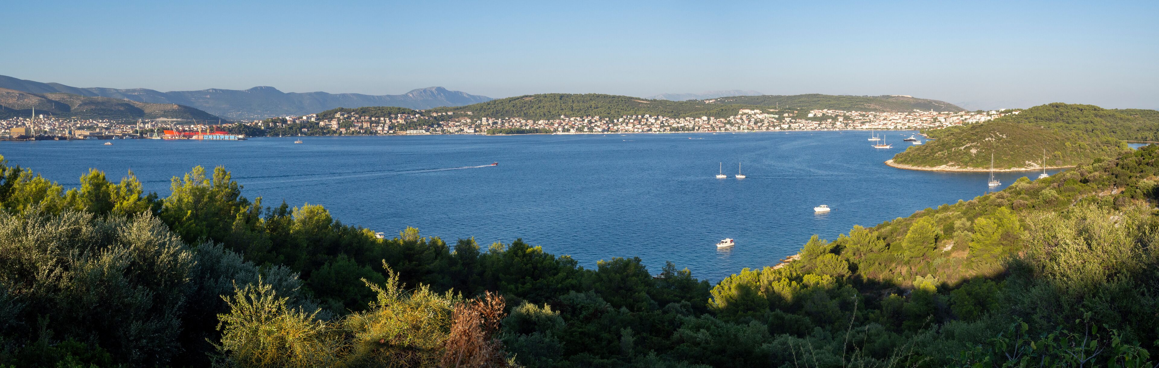 A coastal town with a bay, boats, and a mountainous backdrop.