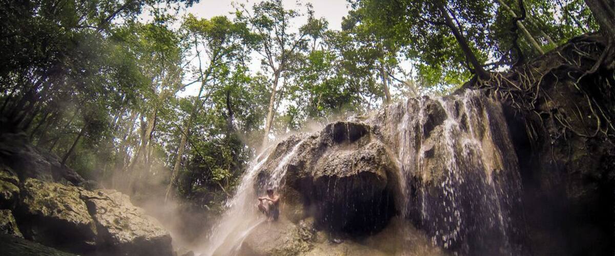 A waterfall cascading over a rocky outcrop surrounded by dense forest.