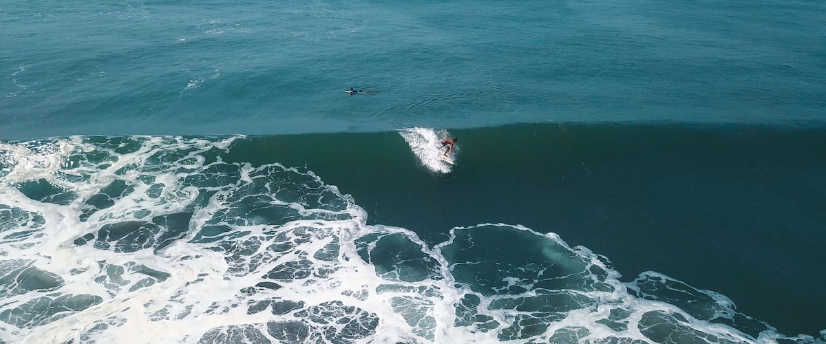 Mesmerizing shot of a surfer at the top of the wave in El Paredon beach in Monterrico, Guatemala