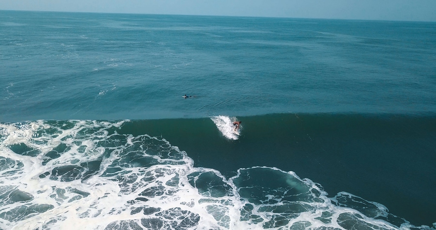 Mesmerizing shot of a surfer at the top of the wave in El Paredon beach in Monterrico, Guatemala