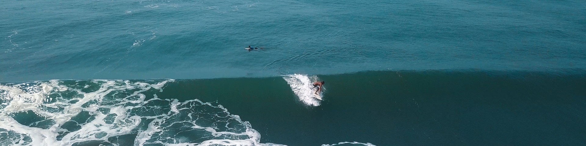 Mesmerizing shot of a surfer at the top of the wave in El Paredon beach in Monterrico, Guatemala