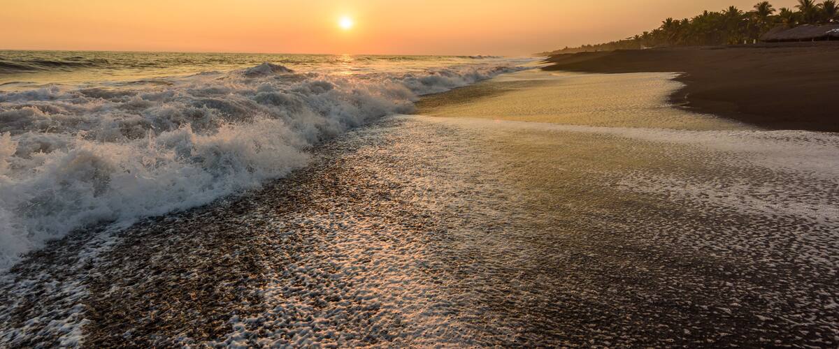 Sunset at Beach with Black Sand in Monterrico, Guatemala. Monterrico is situated on the Pacific coast in the department of Santa Rosa. Known for its volcanic black sand beaches and annual influx of sea turtles. Travel destination of Guatemala.