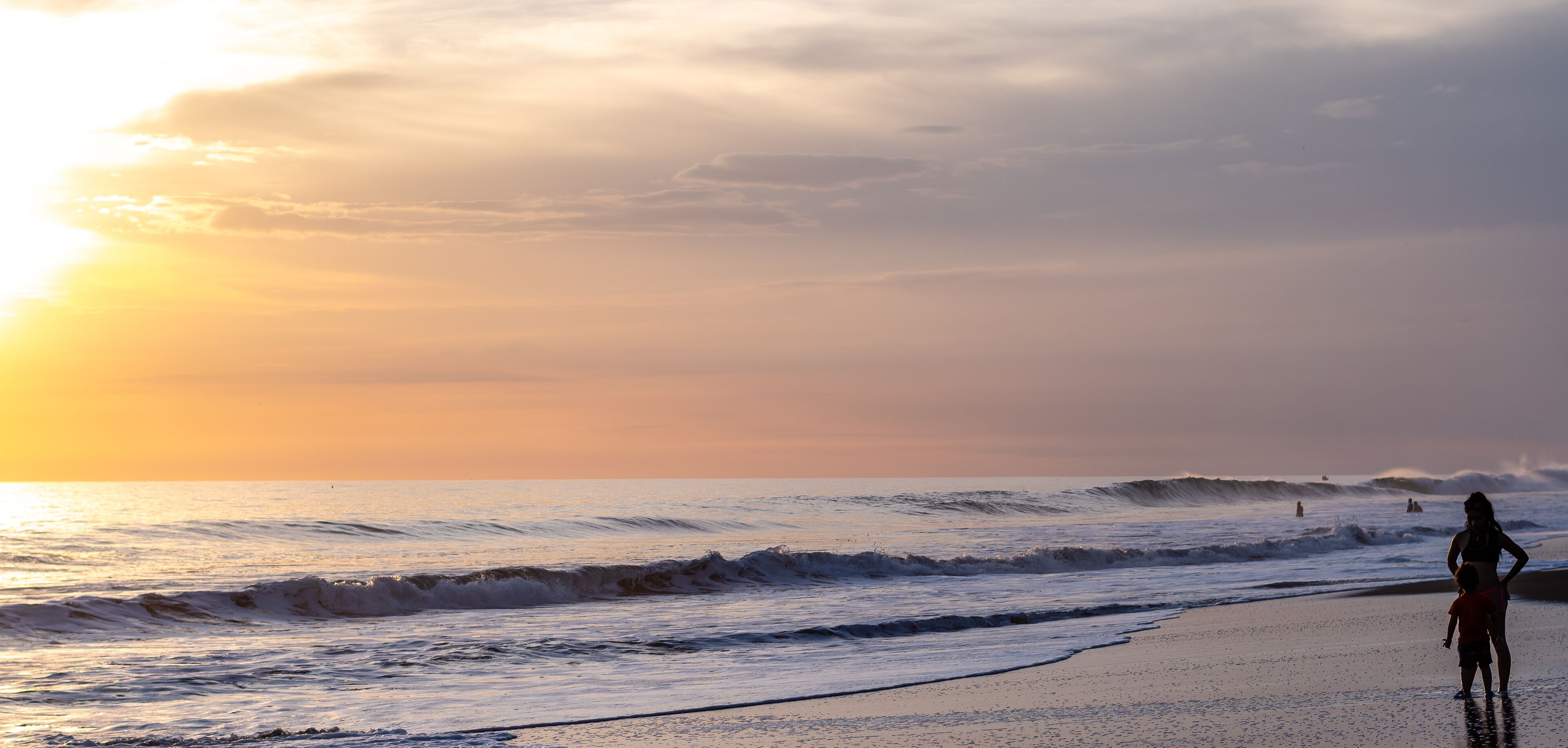 A beach with waves and a sunset.
