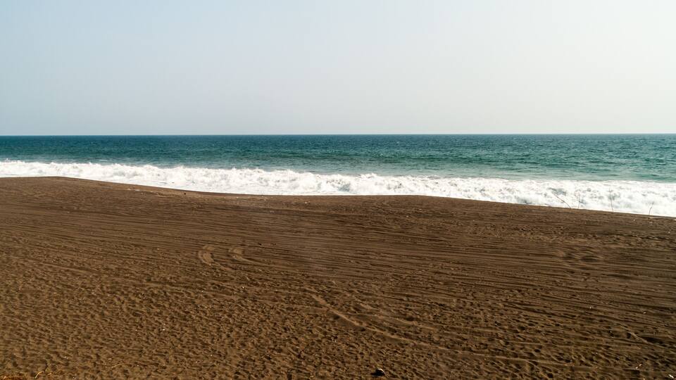 A sandy beach with waves approaching the shore.