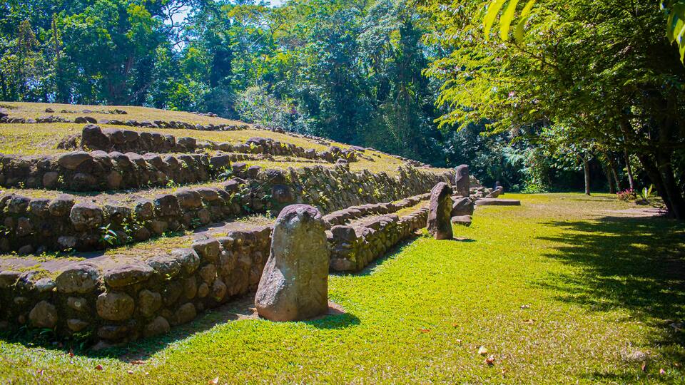A stone pathway leading through a grassy area with a large stone monument in the center.