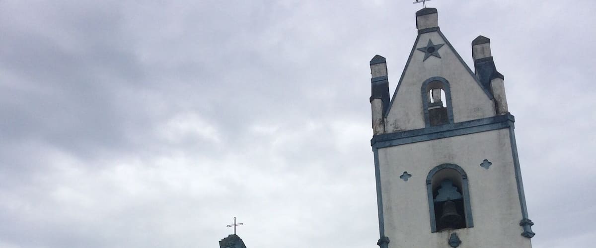 A white church with a blue door and bell tower.