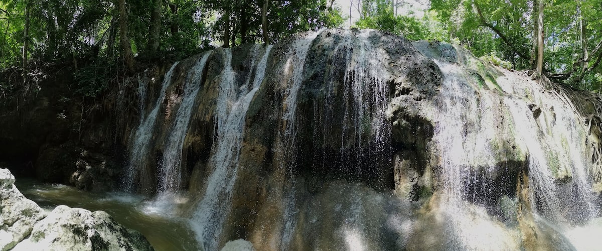 A waterfall cascading over a rocky cliff surrounded by dense forest.