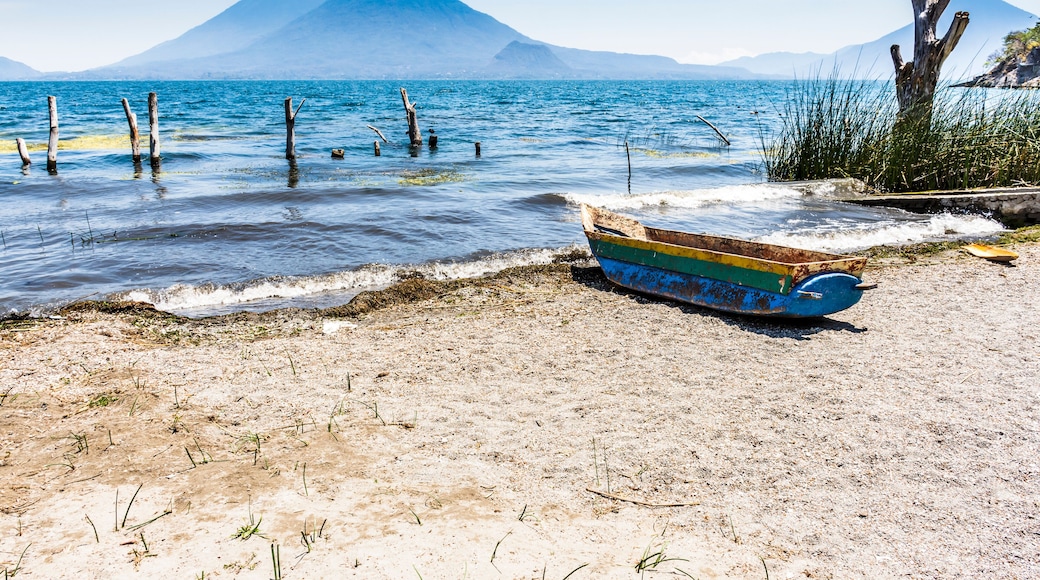 Traditional wooden boat on beach with Toliman & Atitlan volcanoes on horizon in lakeside town of Santa Catarina Palopo, Lake Atitlan, Guatemala.