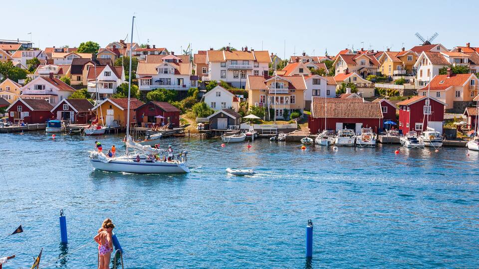 A harbor with boats, a windmill, and colorful houses along the waterfront.