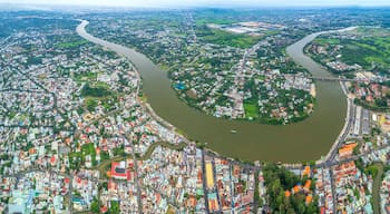 An aerial view of a city with a river meandering through it, surrounded by residential and commercial buildings.