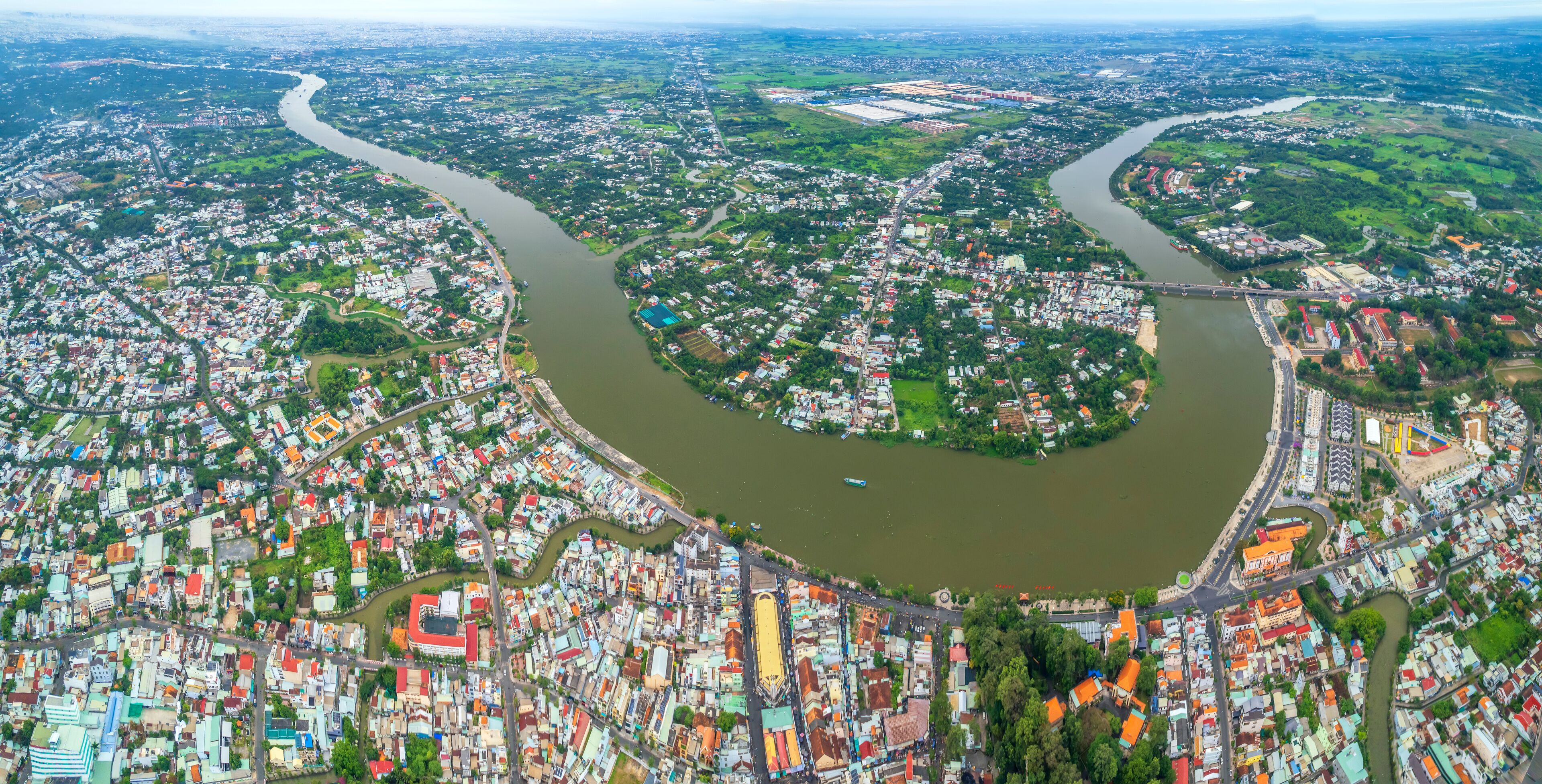 An aerial view of a city with a river meandering through it, surrounded by residential and commercial buildings.