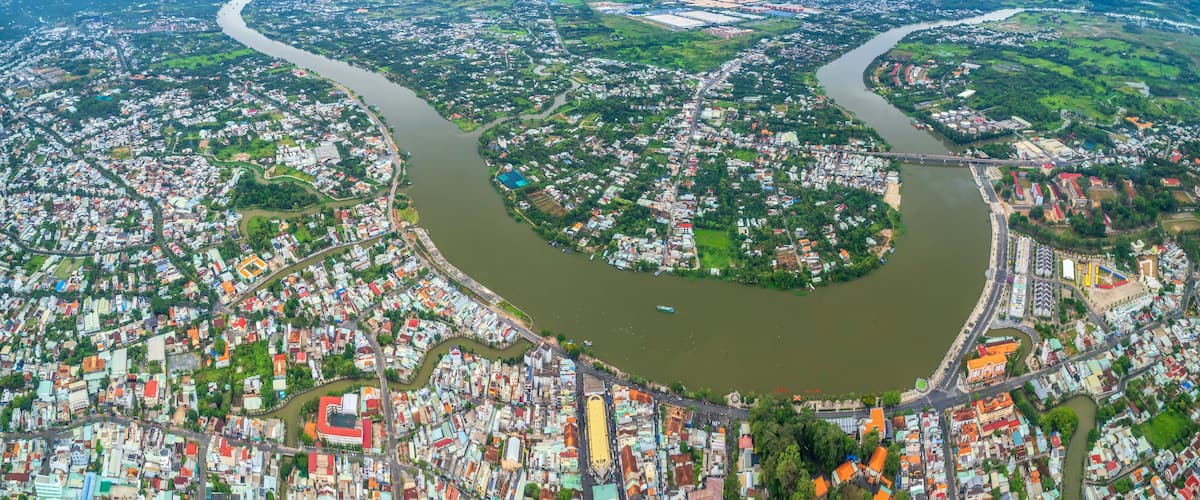 An aerial view of a city with a river meandering through it, surrounded by residential and commercial buildings.