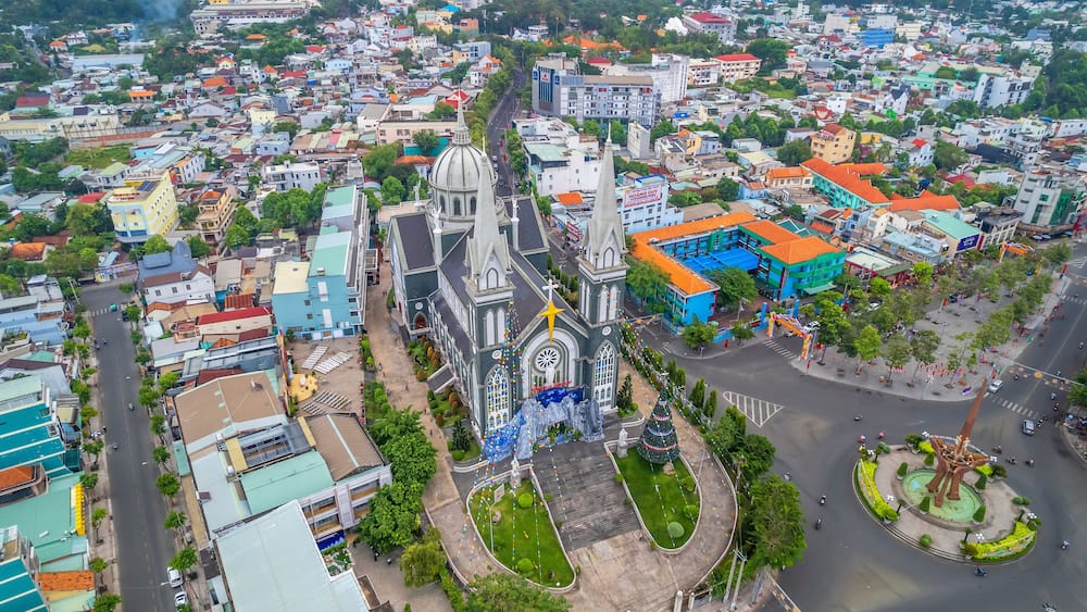 Aerial view of Thu Dau Mot cityscape at morning with church on hill in center. Urban development texture, transport infrastructure and green parks along Be River in Southeast region of Vietnam