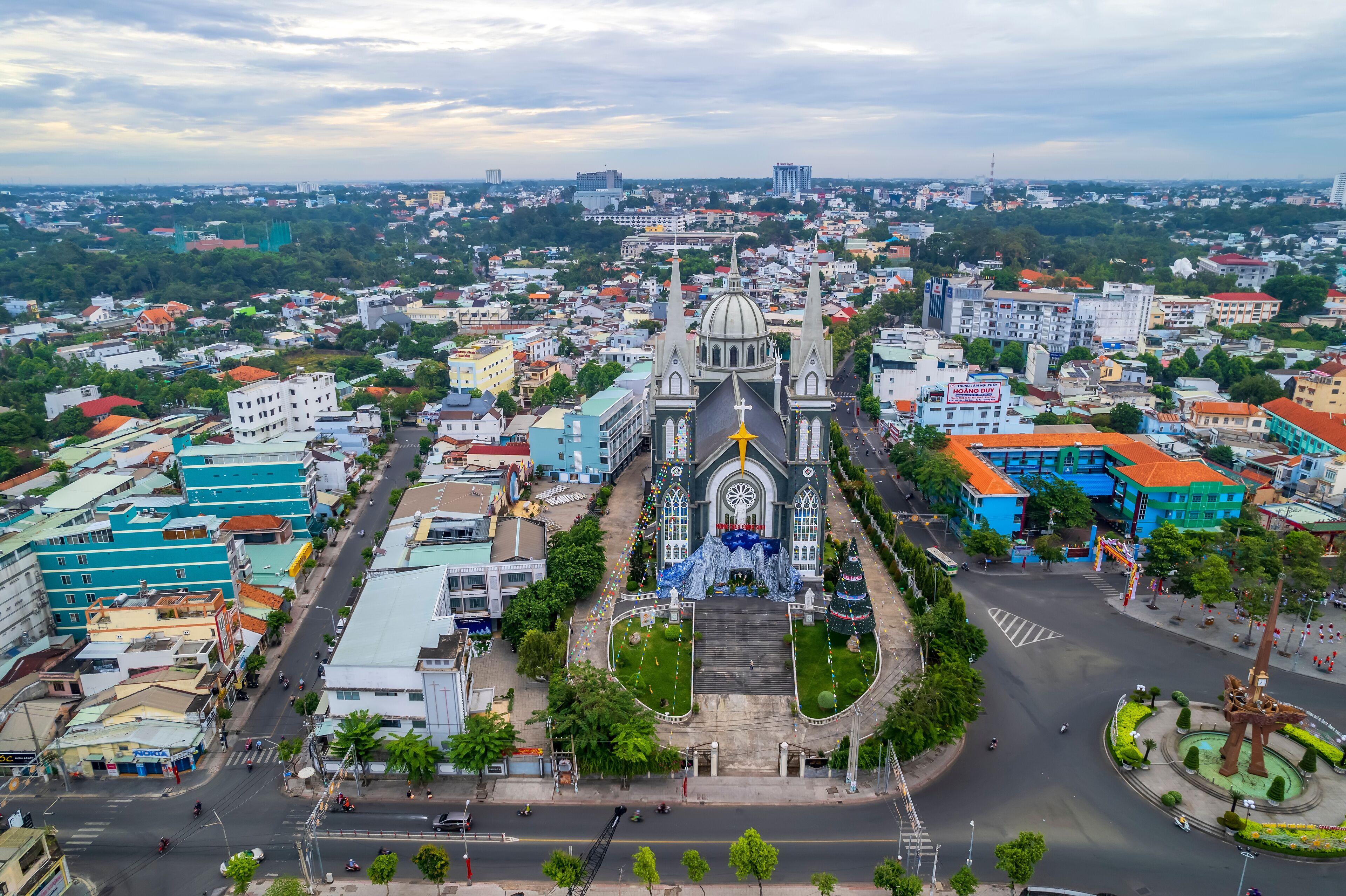Aerial view of Thu Dau Mot cityscape at morning with church on hill in center. Urban development texture, transport infrastructure and green parks along Be River in Southeast region of Vietnam